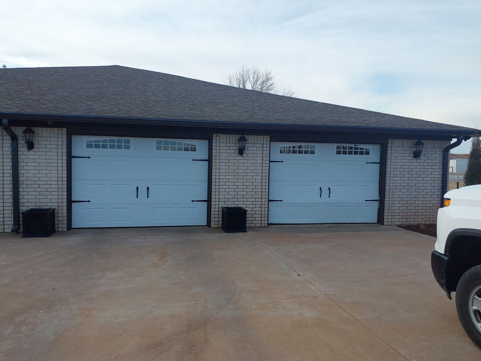 Pair of white carriage-style garage doors installed on a brick home