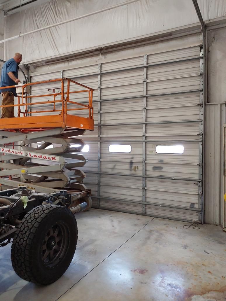 Redneck Doors technician working on a commercial door from a lift