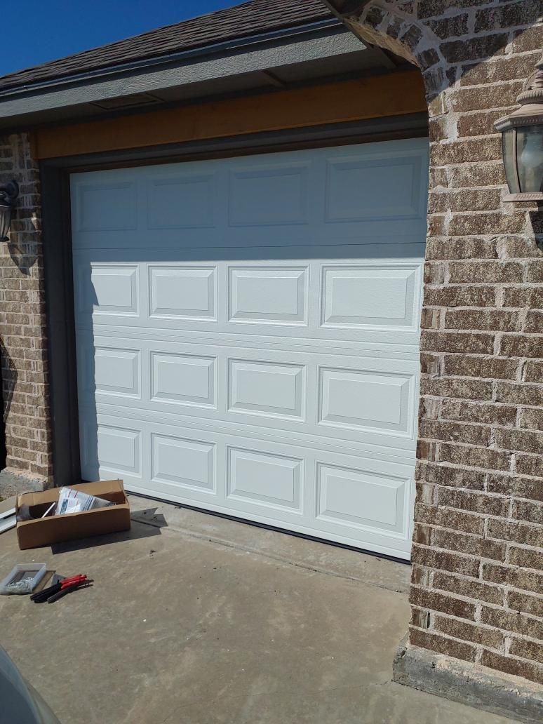 New raised-panel garage door installed on a brick home