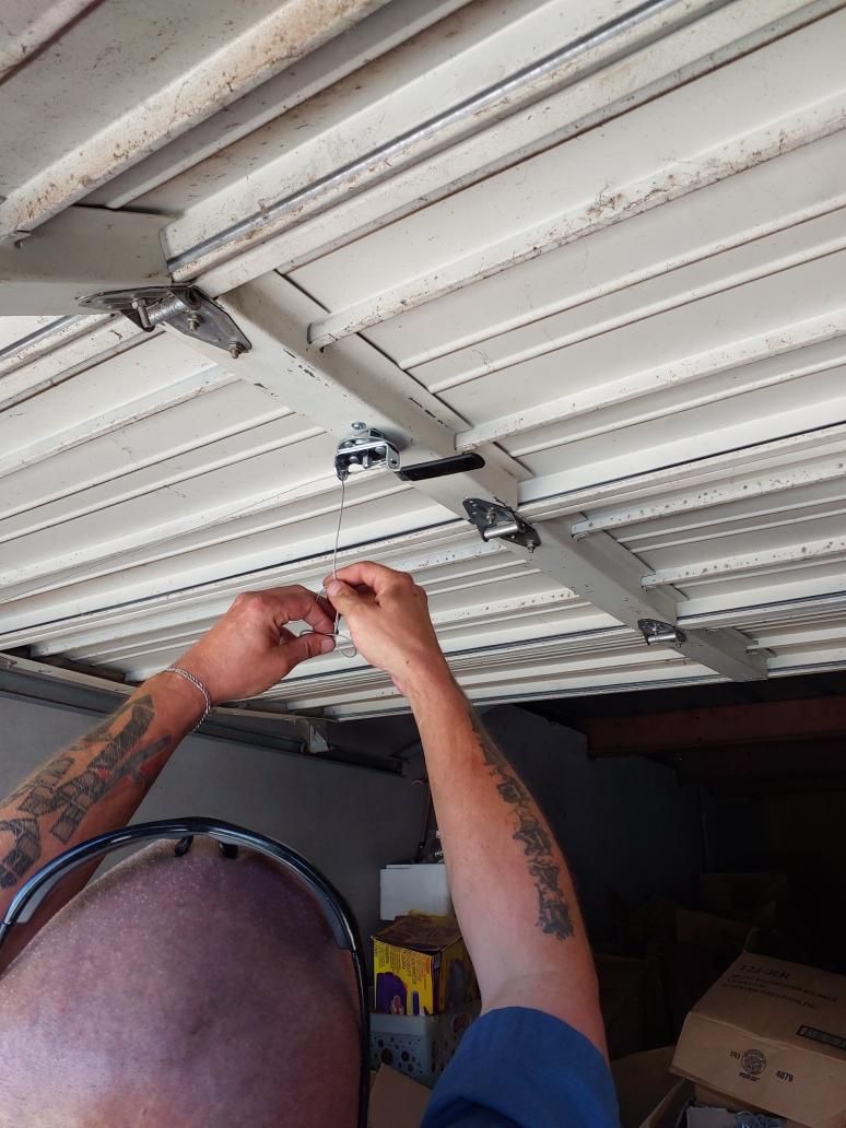 Technician servicing garage door rollers and hinges